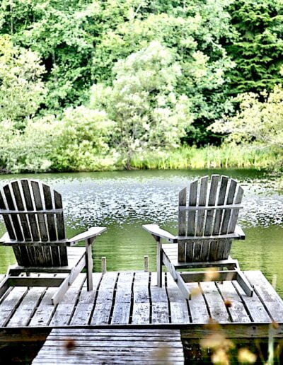 Adirondack chairs on a dock overlooking a lake.