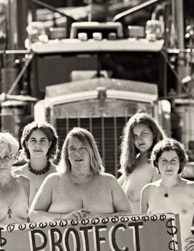 Women protest with sign in front of truck.