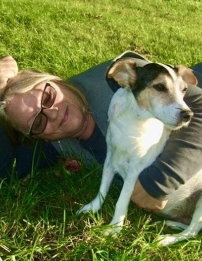 Woman cuddling with dog in grass