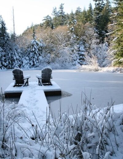 Snow-covered dock with Adirondack chairs